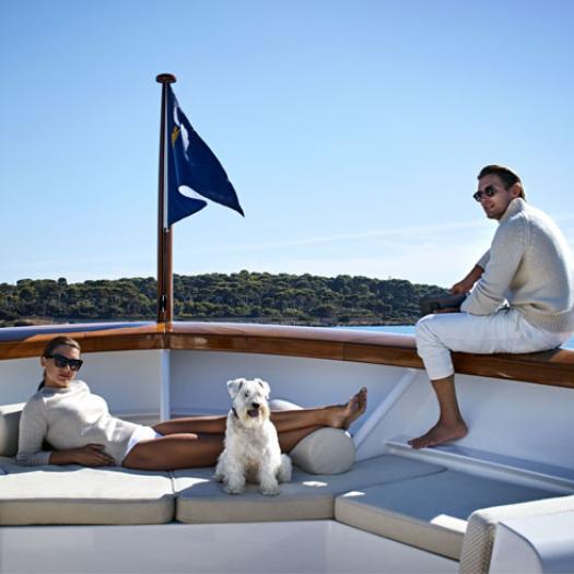 A young couple and their dog relaxing on their yacht.