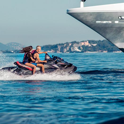 2 people enjoying a jet-ski by the side of their yacht.